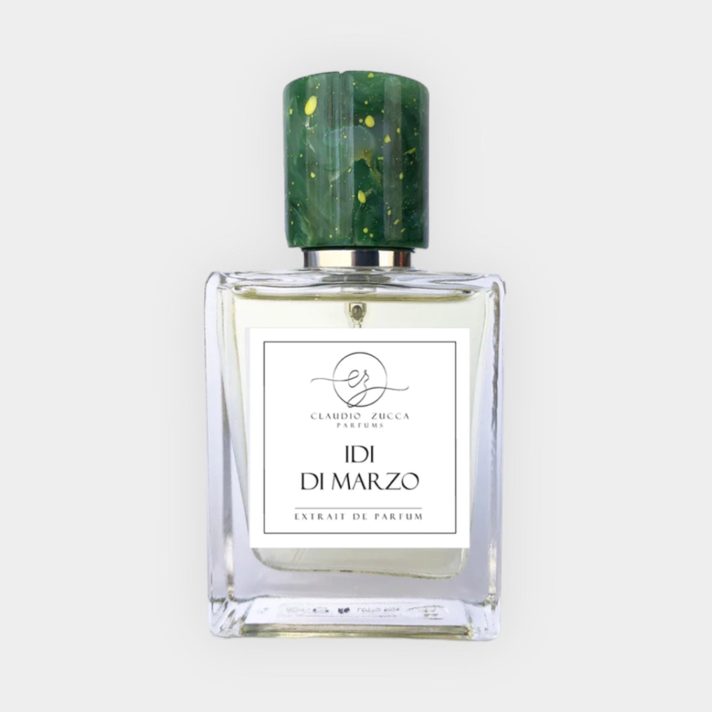 A clear glass bottle of Claudio Zucca Idi Di Marzo Sample, featuring a green speckled cap and a label that reads IDI DI MARZO Extrait de Parfum.