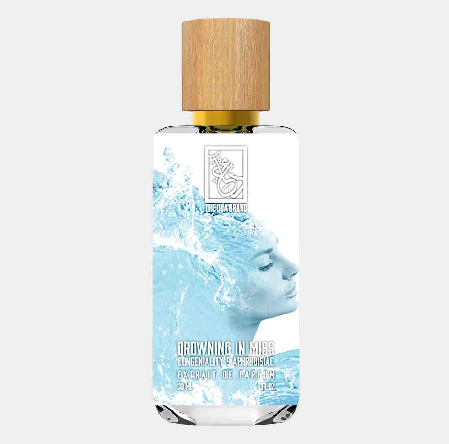 A sleek bottle of Dua Drowning in Miss Congeniality Aphrodisiac, featuring a woman's serene face partially submerged in water on the label. The bottle is topped with a wooden cap, and the design conveys a refreshing and inviting aesthetic.