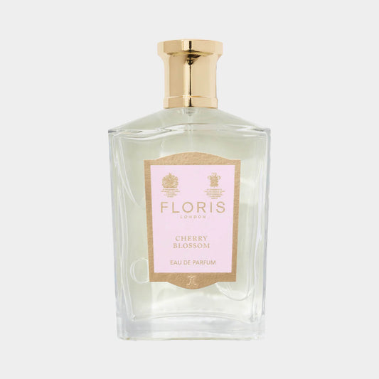 A clear glass bottle of Floris London Cherry Blossom perfume, featuring a gold cap and a soft pink label, showcasing the fragrance's elegant design.