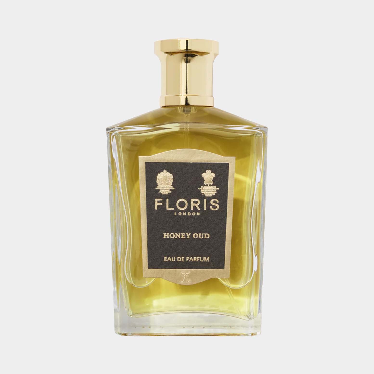 A clear glass bottle of Floris London Honey Oud perfume, featuring a gold cap and a black and gold label, showcasing its luxurious scent with hints of honey and oud.