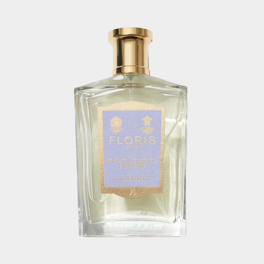 A clear glass bottle of Floris London Night Scented Jasmine fragrance, featuring a gold cap and a light blue label with elegant typography. The scent is classified as Eau de Toilette.