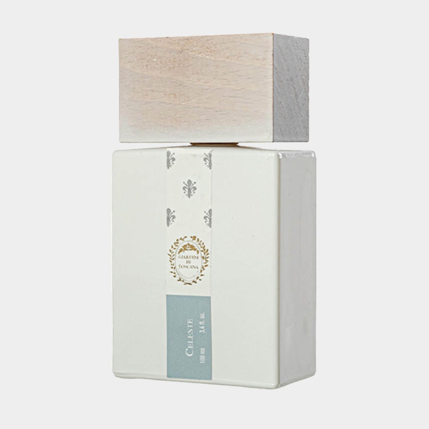 A full bottle of Giardini di Toscana Celeste, featuring a sleek white ceramic design with a natural wood cap. The label displays elegant floral motifs and a soft blue accent.