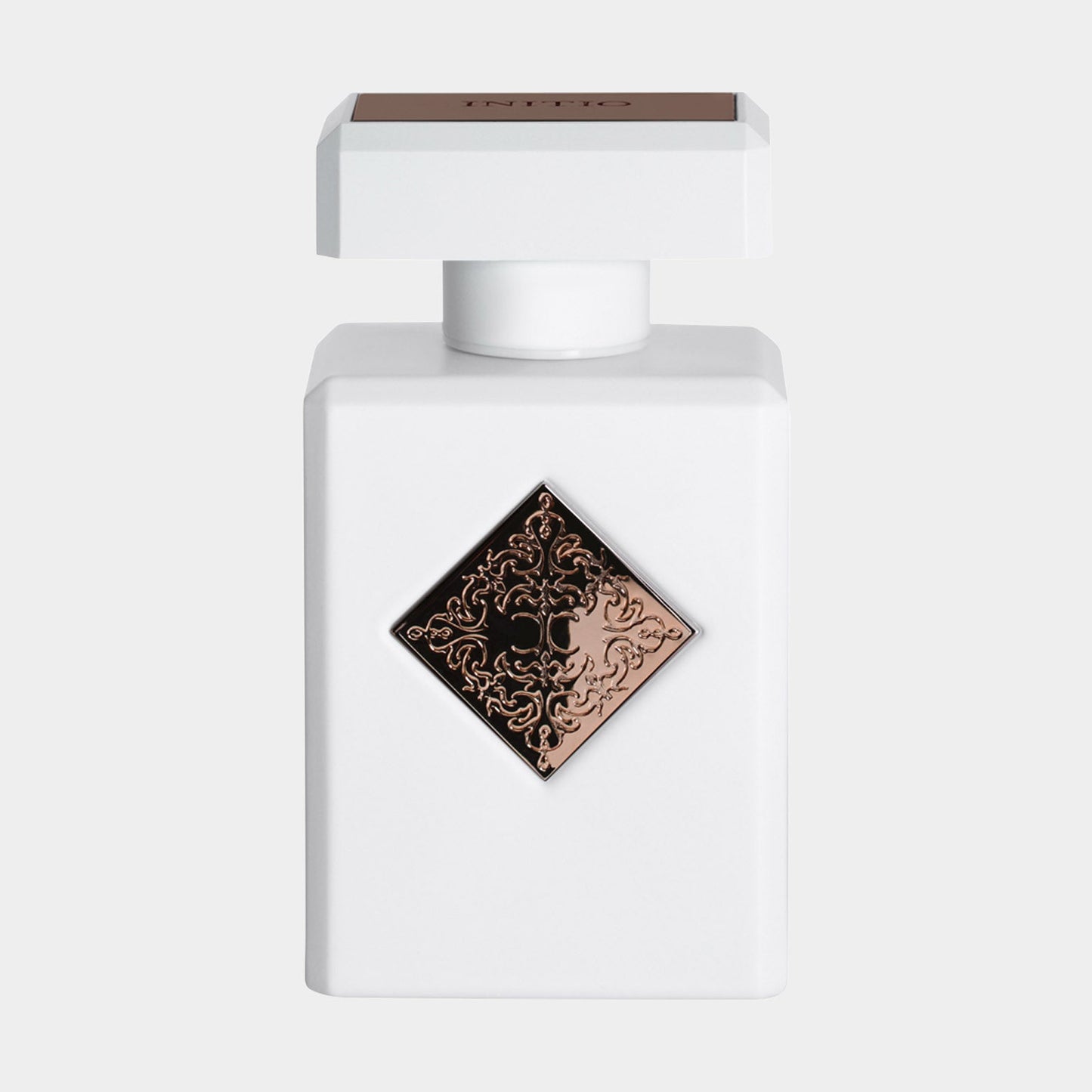 A sleek white bottle of Initio Paragon Sample, featuring an elegant diamond-shaped emblem in copper on the front, showcasing its luxurious design.