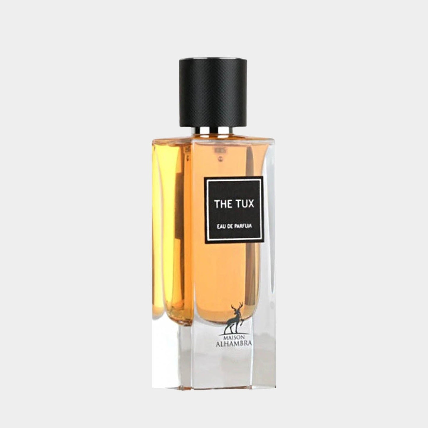 A full bottle of Maison Alhambra The Tux Eau de Parfum, featuring a clear glass design with stylish black accents and a sleek, modern silhouette. The fragrance inside is a warm amber hue, suggesting a sophisticated scent profile.