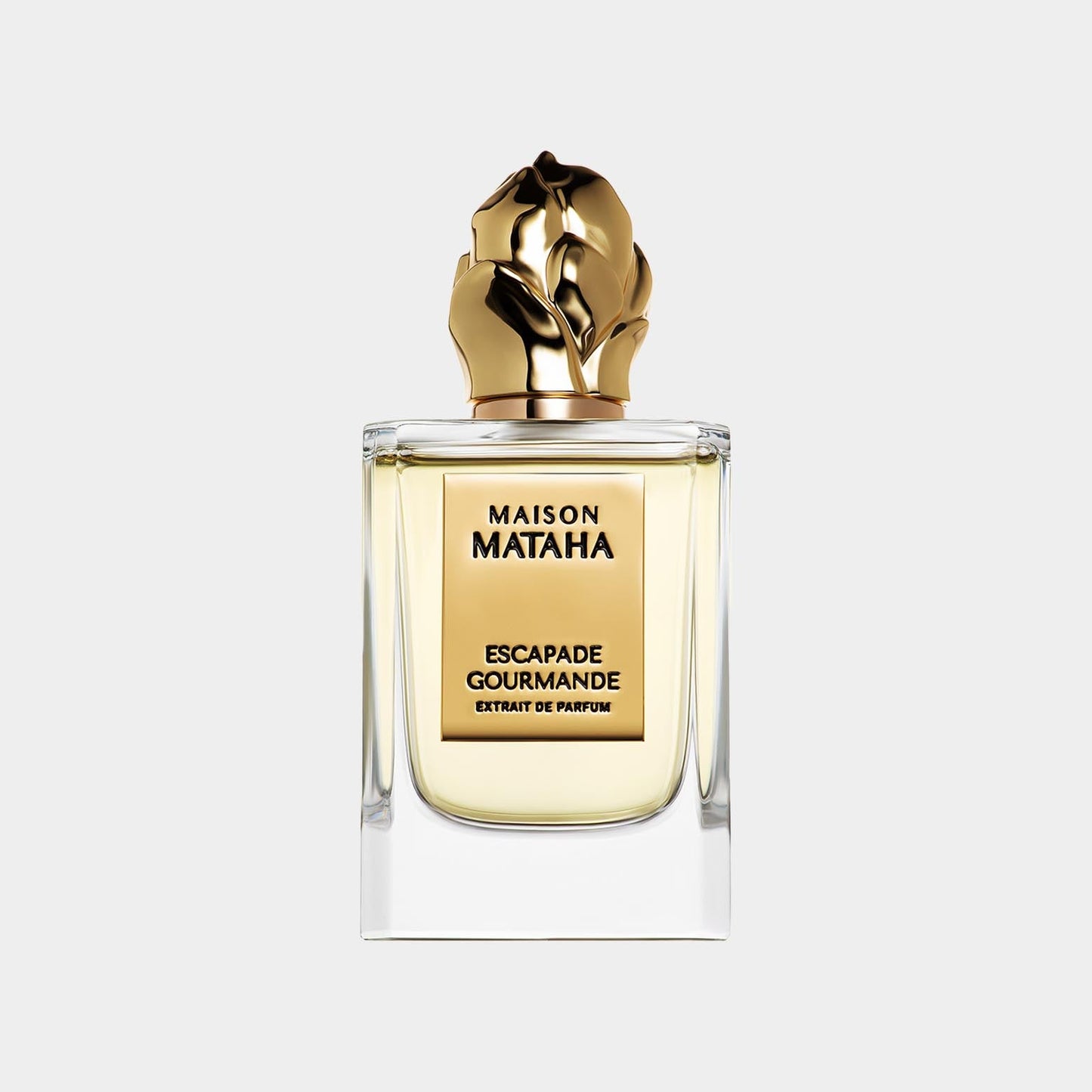 A luxurious perfume bottle featuring a golden, sculptural cap, showcasing the 'Maison Mataha Escapade Gourmande Sample' fragrance in an elegant clear glass container.