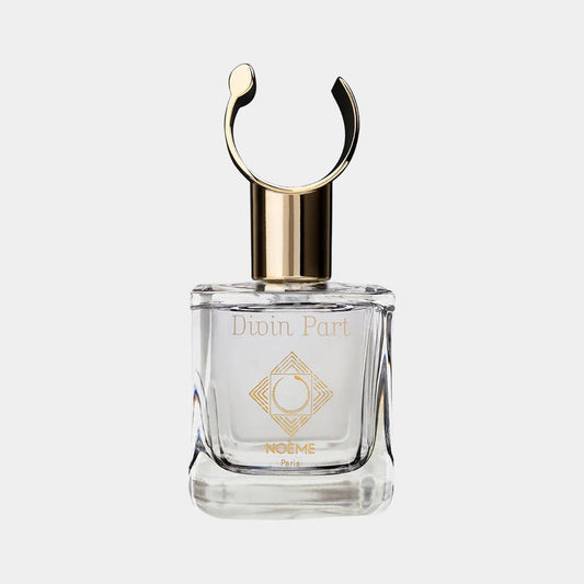 A glass perfume bottle of Noème Paris Divin Part Sample, featuring a decorative metallic cap and an elegant design with a logo on the front. The bottle is set against a light background, emphasizing its luxurious appearance.