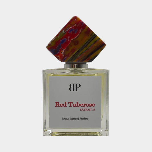 A stylish perfume bottle of Bruno Perrucci Red Tuberose Sample, featuring a striking, multicolored cap and a clear glass body with a label that reads Red Tuberose EXTRACT 33.