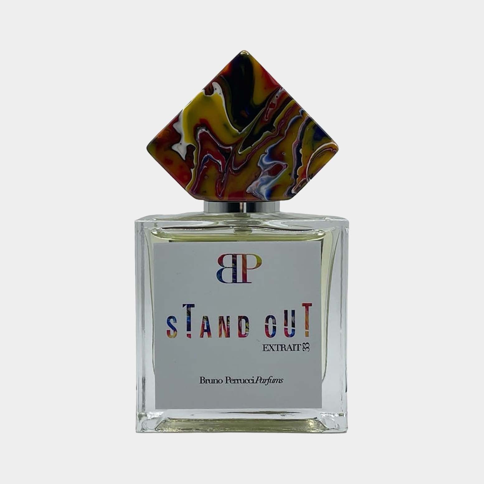 A full bottle of Bruno Perrucci Stand Out perfume, featuring a transparent glass design with a colorful, geometric cap, displaying the brand logo and bold text on the label.