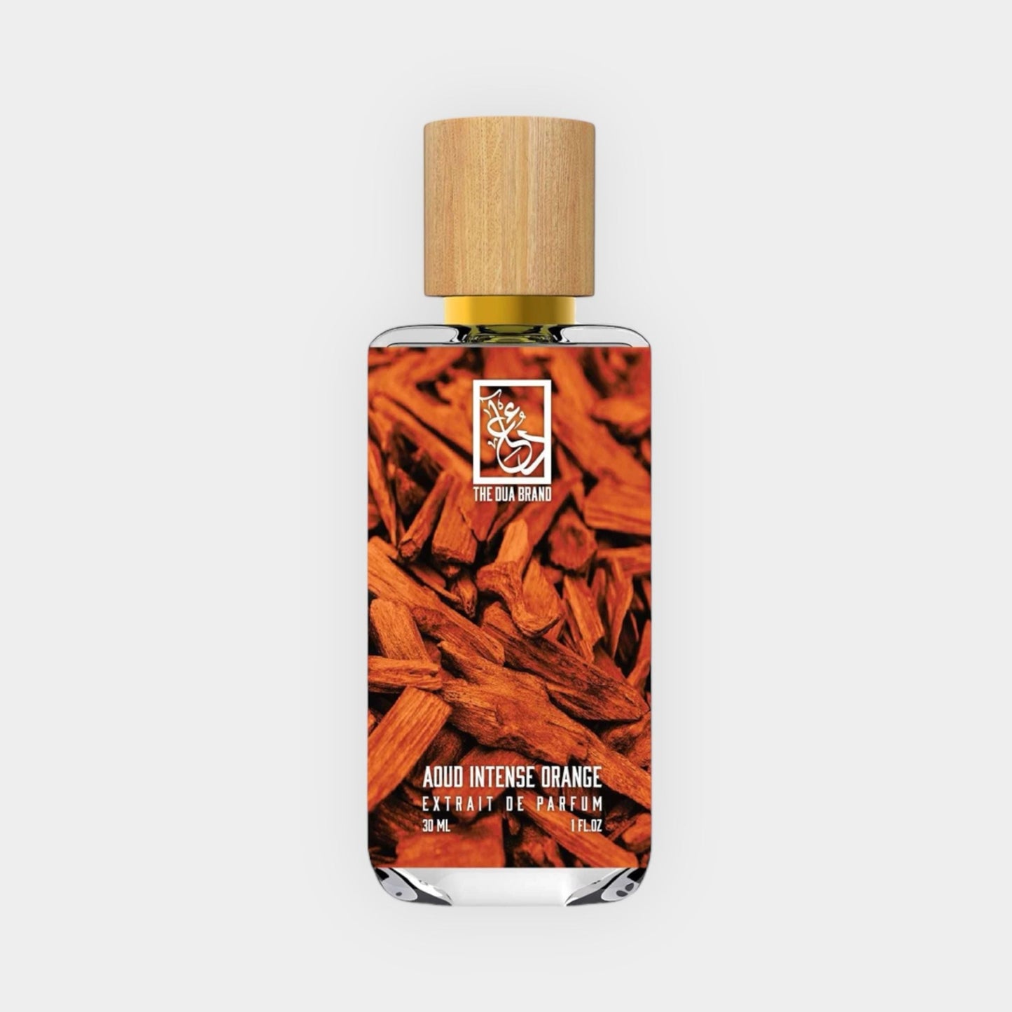 A bottle of Dua Aoud Intense Orange Sample, featuring a wooden cap and surrounded by aromatic, reddish-brown wood shavings. The label highlights its rich, intense fragrance profile.