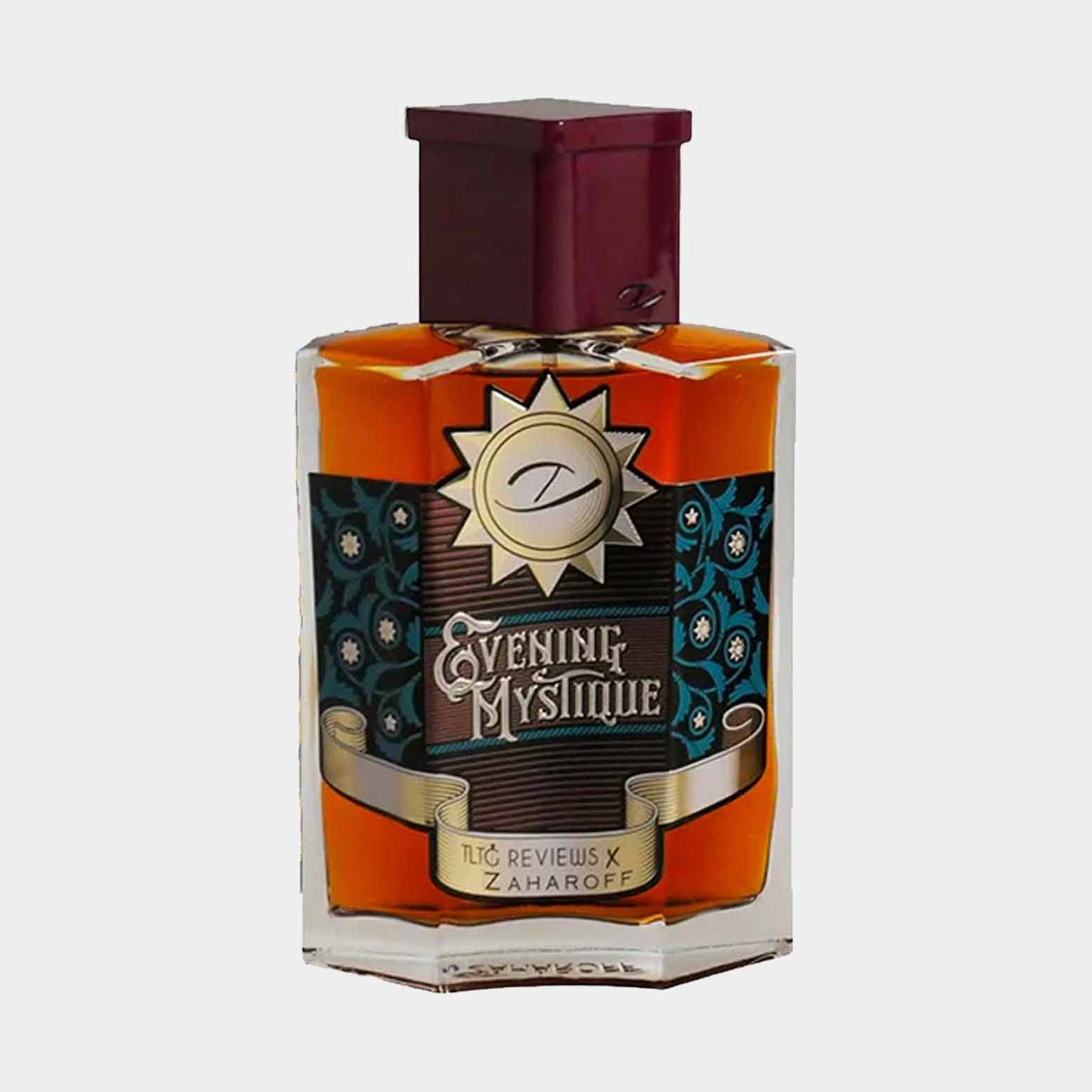A small bottle of Zaharoff Evening Mystique Sample perfume, featuring an elegant design with a prominent sun emblem and rich amber liquid, set against a simple white background.