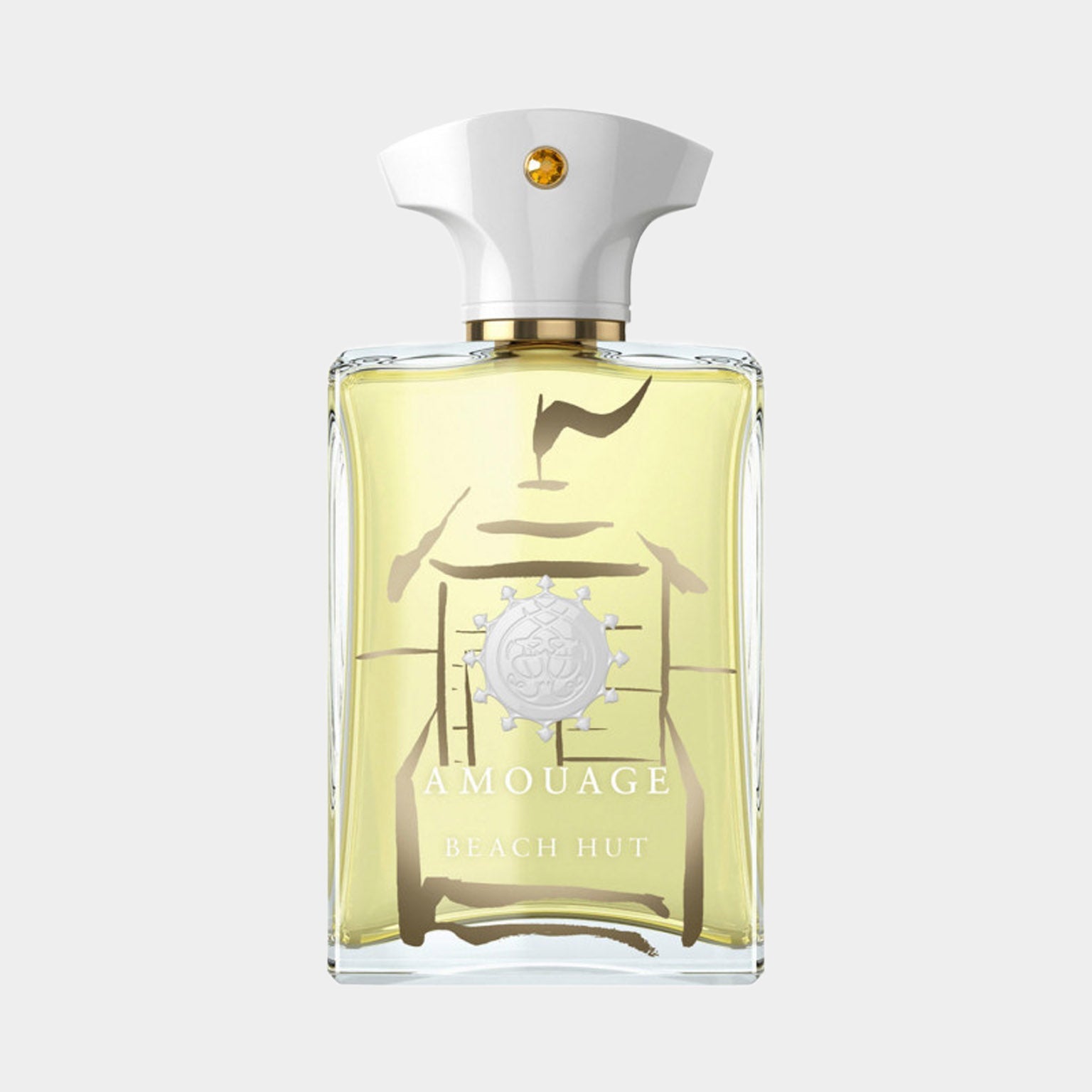 A clear glass bottle of Amouage Beach Hut Man Made in Oman, featuring a white cap and a minimalist design with a light yellow fragrance inside. The bottle showcases the brand's emblem prominently on the front.