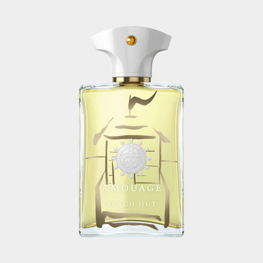 A clear glass bottle of Amouage Beach Hut Man Made in Oman, featuring a white cap and a minimalist design with a light yellow fragrance inside. The bottle showcases the brand's emblem prominently on the front.