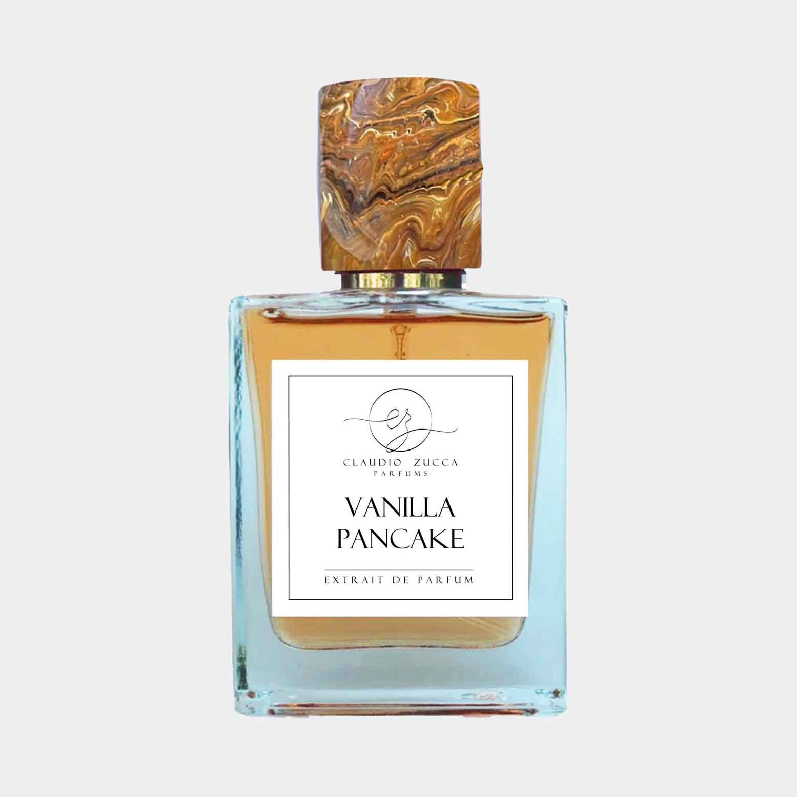 A bottle of Claudio Zucca Vanilla Pancake Sample perfume, featuring a decorative, marbled cap and a clear glass base showcasing the amber fragrance. The label prominently displays the product name in an elegant font.