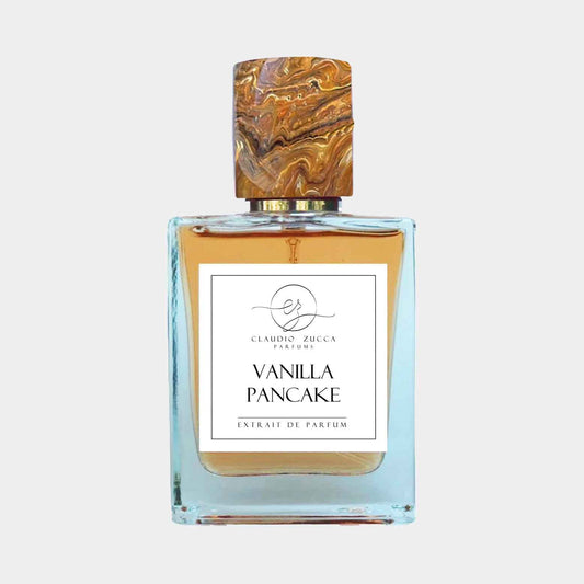 A bottle of Claudio Zucca Vanilla Pancake Sample perfume, featuring a decorative, marbled cap and a clear glass base showcasing the amber fragrance. The label prominently displays the product name in an elegant font.