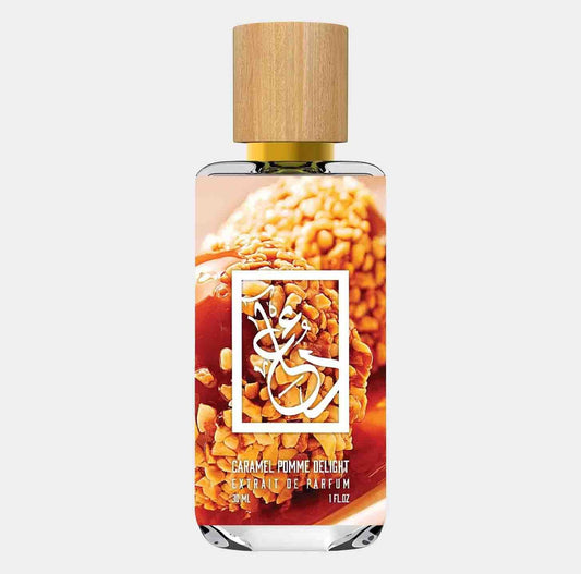 A glass bottle of Dua Caramel Pomme Delight fragrance, featuring a wooden cap and a vibrant label showcasing caramel and apple treats in the background. The bottle holds 30ml of perfume.