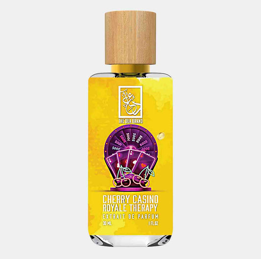 A bottle of Dua Cherry Casino Royale Therapy Sample, featuring a vibrant yellow label with cherry illustrations and playing cards, housed in a sleek glass container with a wooden cap. The bottle holds 30 ml of extrait de parfum.