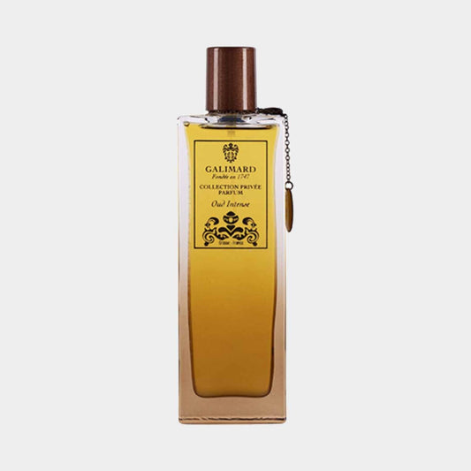 A bottle of Galimard Oud Intense from the Collection Privée, featuring an elegant design with a wooden cap and a decorative charm, containing a rich, golden fragrance.