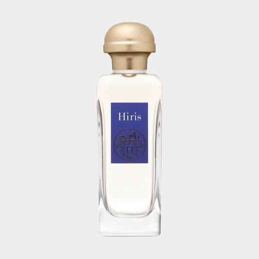 A small bottle of Hermès Hiris perfume sample, featuring a clear glass design with a gold cap and a blue label. The label displays the Hermès emblem and the name Hiris.