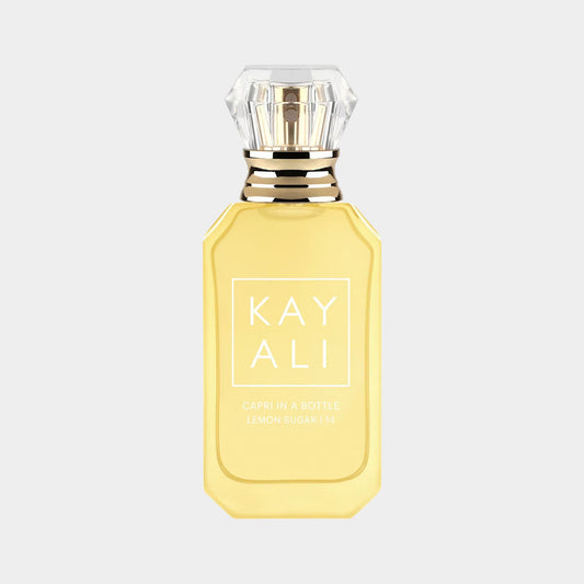 A glass bottle of Kayali Capri In A Bottle Lemon Sugar 14, featuring a bright yellow liquid and a diamond-shaped cap. The bottle is elegantly designed with a minimalist label displaying the brand name and fragrance title.