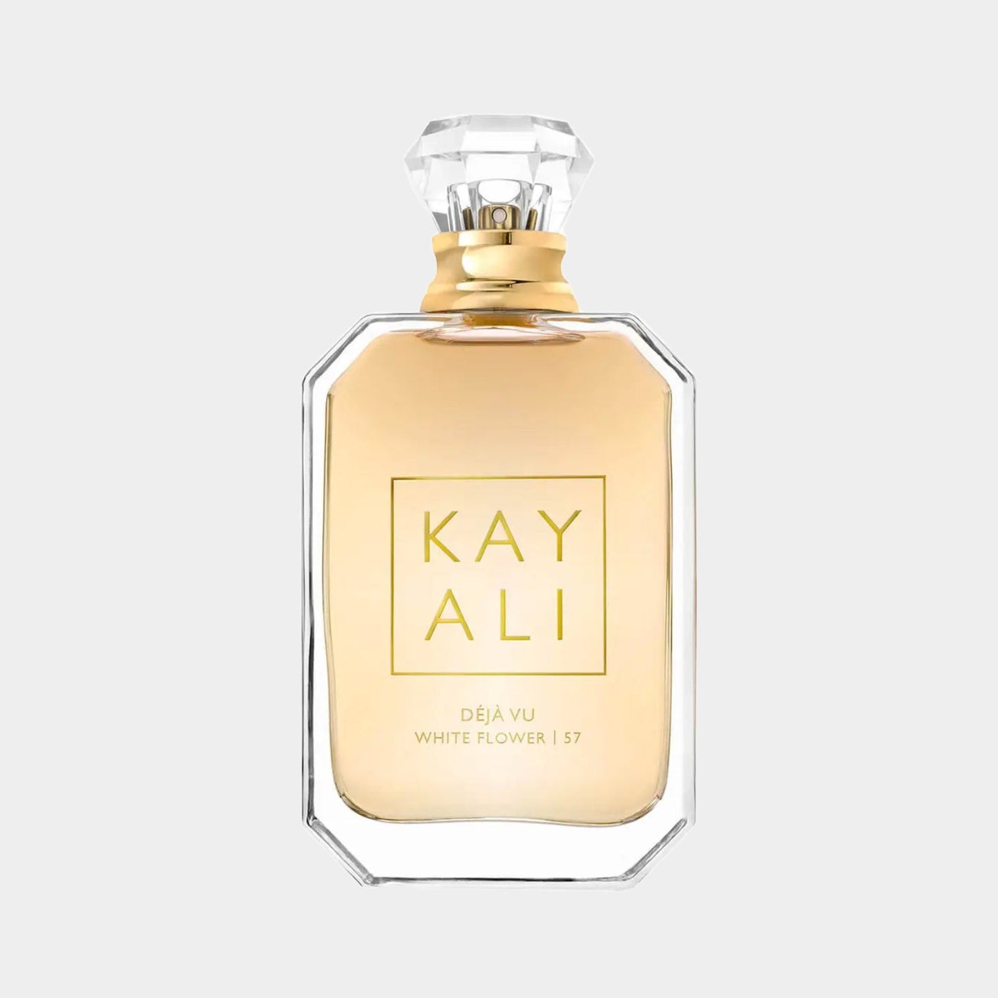 A sleek, elegant bottle of Kayali Déjà Vu White Flower 57 perfume, featuring a gold cap and a clear glass design that showcases the light golden fragrance inside.