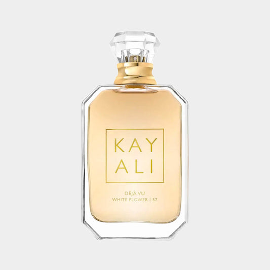 A sleek, elegant bottle of Kayali Déjà Vu White Flower 57 perfume, featuring a gold cap and a clear glass design that showcases the light golden fragrance inside.