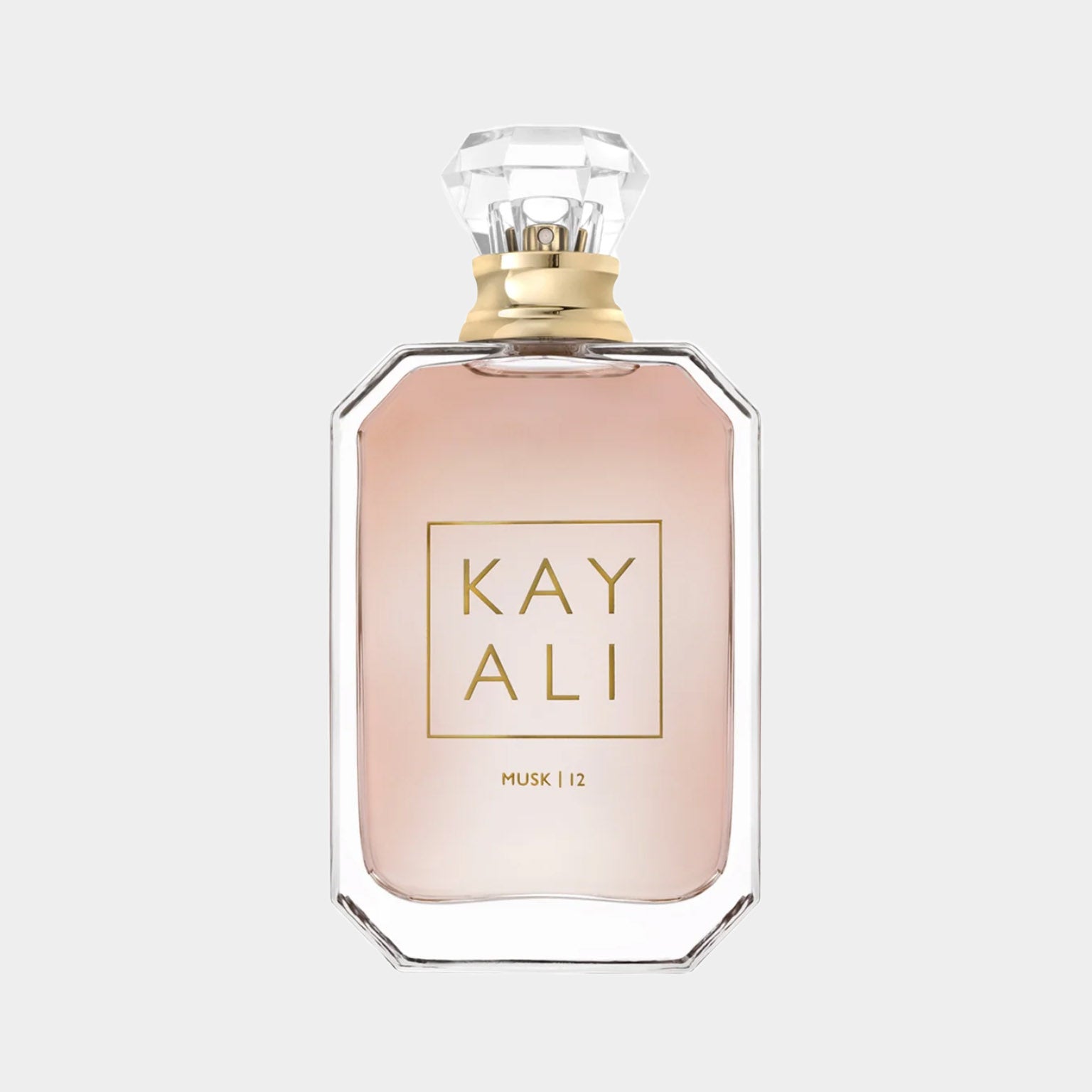 A clear glass bottle of Kayali Musk 12, featuring a stylish diamond-shaped cap and elegant label. The fragrance has a soft, pink hue, embodying a luxurious and sophisticated scent.