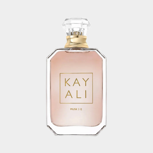 A clear glass bottle of Kayali Musk 12, featuring a stylish diamond-shaped cap and elegant label. The fragrance has a soft, pink hue, embodying a luxurious and sophisticated scent.