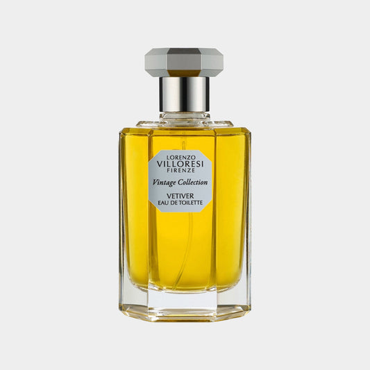 A glass bottle of Lorenzo Villoresi Vetiver Eau de Toilette, featuring a geometric silver cap and a vintage label, filled with a golden yellow fragrance. The elegant design reflects a classic and sophisticated style.