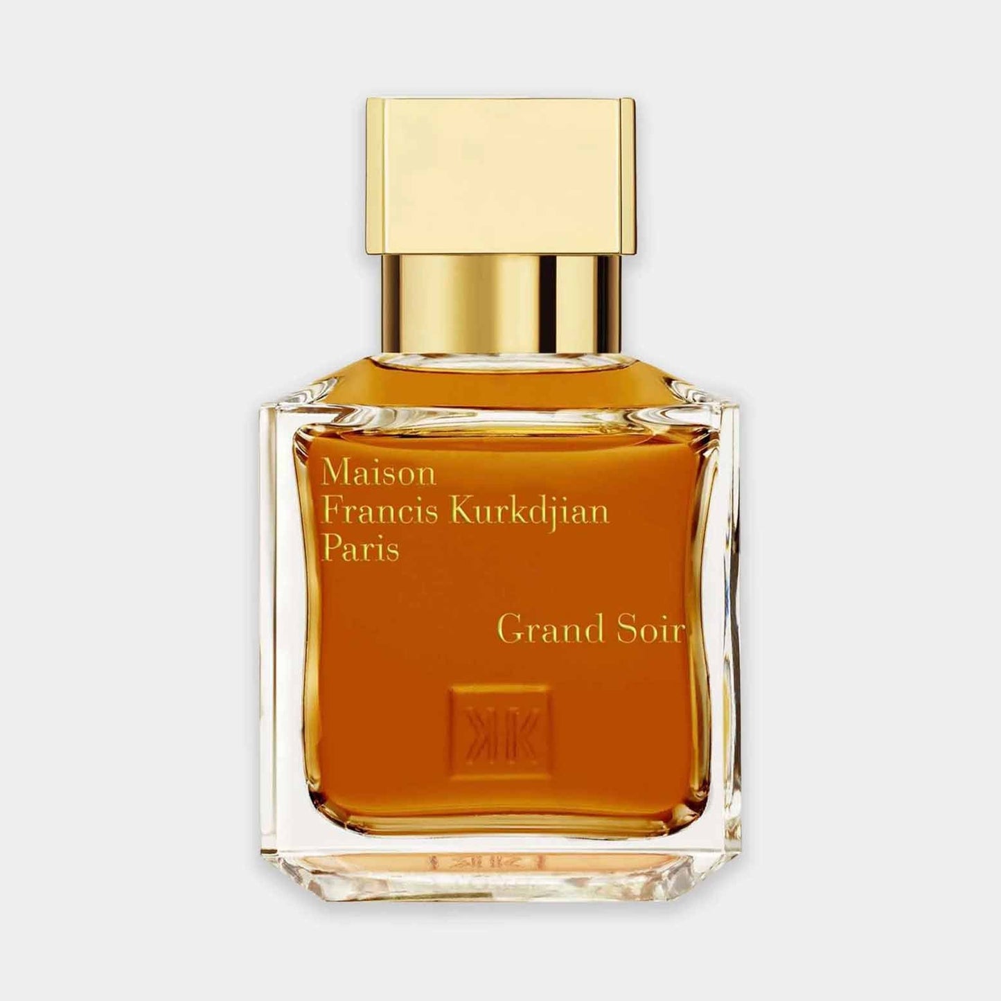 A small glass bottle of Maison Francis Kurkdjian Grand Soir perfume, featuring a rectangular design with a sleek gold cap and rich amber liquid.