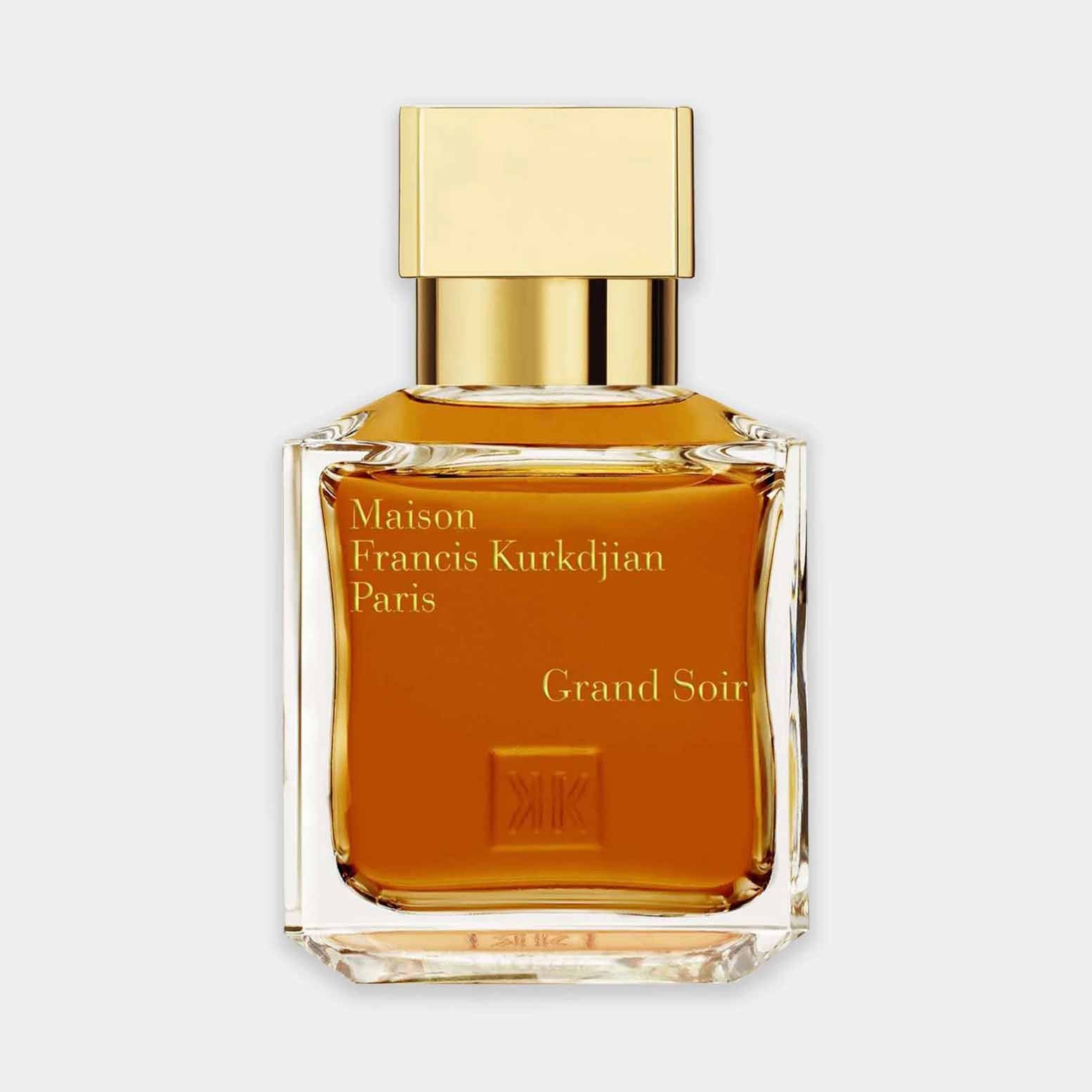 A small glass bottle of Maison Francis Kurkdjian Grand Soir perfume, featuring a rectangular design with a sleek gold cap and rich amber liquid.