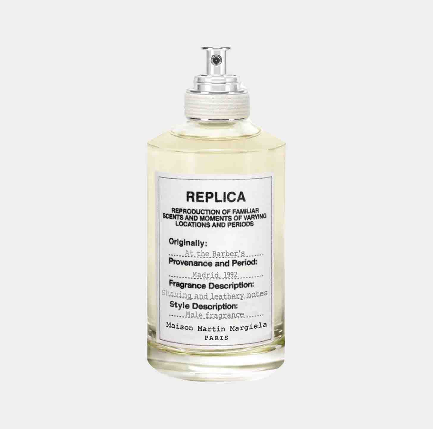 A bottle of Maison Martin Margiela Replica At the Barber's Sample fragrance, featuring a clear glass design and a label detailing the scent's provenance, fragrance descriptors, and style description.