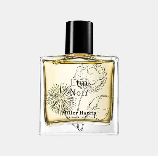 A clear glass bottle of Miller Harris Étui Noir perfume, featuring an elegantly illustrated label with floral and botanical designs. The yellow liquid inside the bottle reflects its exquisite fragrance.