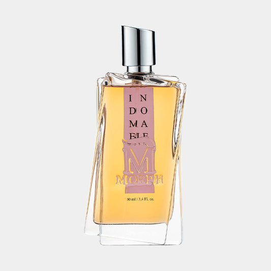 A sleek glass perfume bottle labeled Indomable Morph Sample with a soft amber liquid inside, featuring a modern design and a silver spray nozzle.