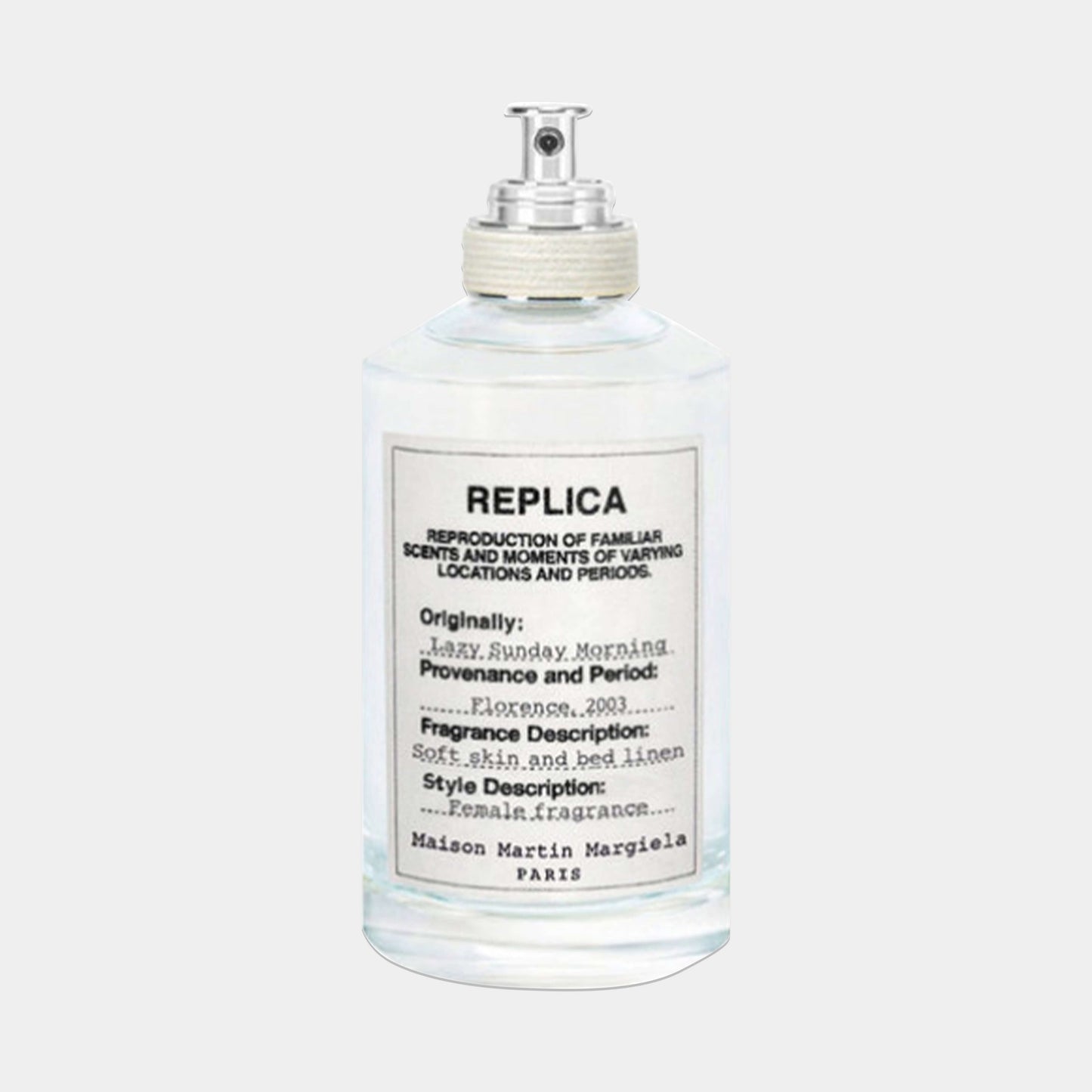 A clear glass bottle of Maison Martin Margiela Replica Lazy Sunday Morning Sample fragrance, featuring a minimalist label that describes its soft, floral scent inspired by fresh linen.