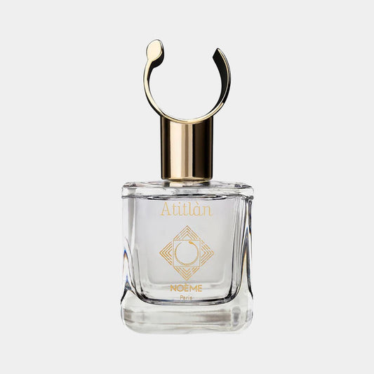 A clear glass perfume bottle with a gold cap and an elegant, minimalist design, featuring the label Noème Paris Atitlan Sample. The bottle has a unique circular top detail, enhancing its sophisticated appearance.