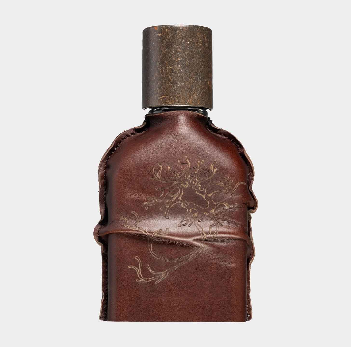 A small, brown leather-wrapped bottle of Orto Parisi Cuoium Sample, featuring an ornate design on the leather and a metallic cap. The unique packaging highlights the luxurious and artisanal nature of the fragrance.