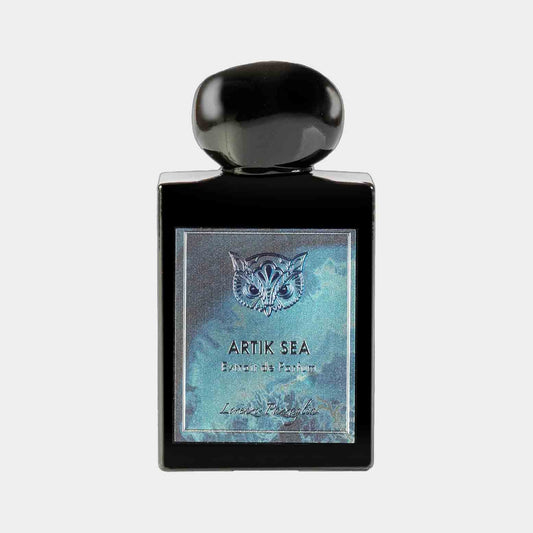 A sleek black perfume bottle labeled 'Lorenzo Pazzaglia Artik Sea Sample,' featuring an elegant owl design on the front. The bottle has a rounded black cap and showcases a shimmering blue background.