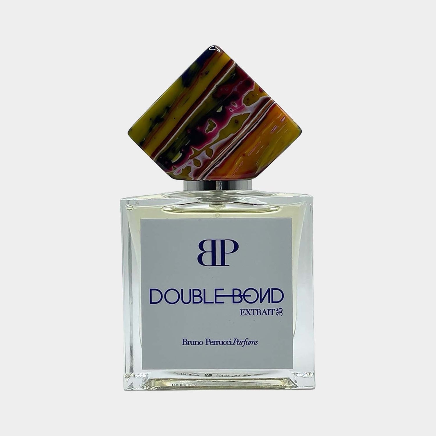A full bottle of Bruno Perrucci Double Bond perfume, featuring an elegant square glass design and a uniquely colorful geometric cap. The label prominently displays the name Double Bond in blue lettering.