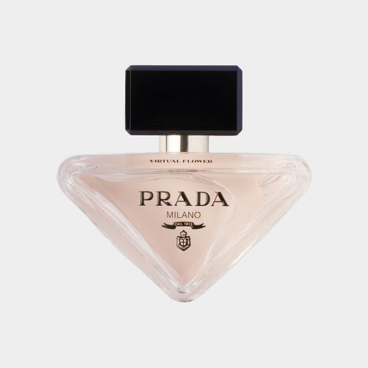 A bottle of Prada Paradoxe Virtual Flower Sample, featuring a unique triangular shape with a sleek black cap and elegant branding in gold. The fragrance inside is a soft pink hue, showcasing the luxurious design.