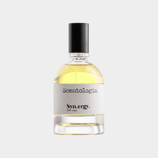 A clear glass bottle of Scentologia Syn.ergy Sample featuring a slender neck and black cap, showcasing a light yellow fragrance inside. The label is minimalist, displaying the brand name and product title.