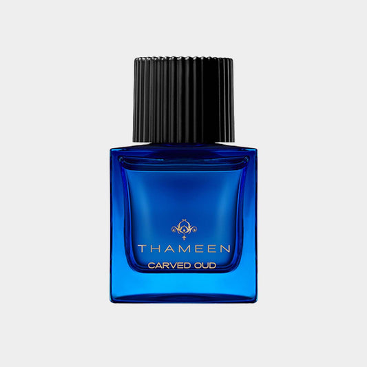 A blue glass bottle featuring the label Thameen Carved Oud, designed for holding a luxurious oud fragrance sample, topped with a ridged black cap.