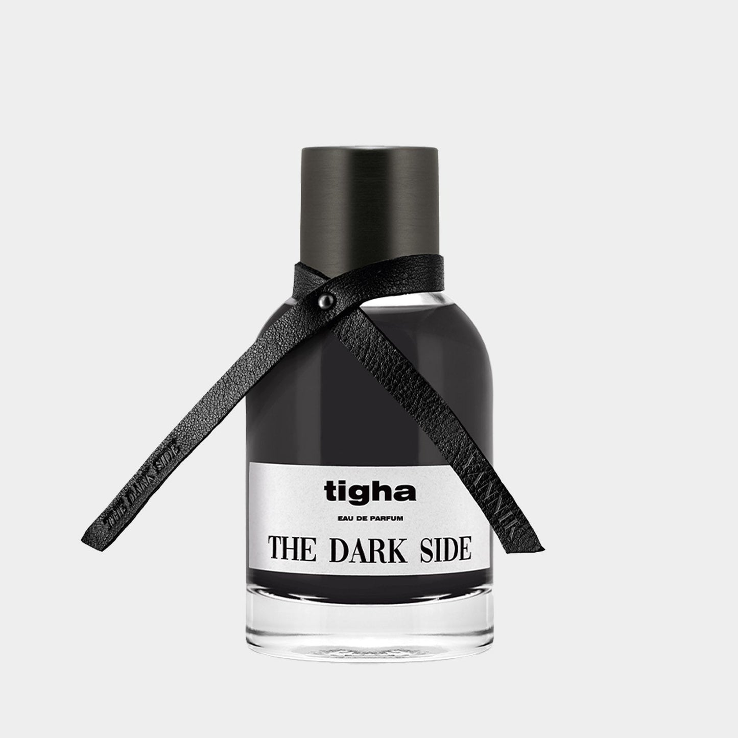 A sleek black perfume bottle labeled Tigha The Dark Side Sample, featuring an elegant leather ribbon around the neck, conveying a sense of mystery and sophistication.