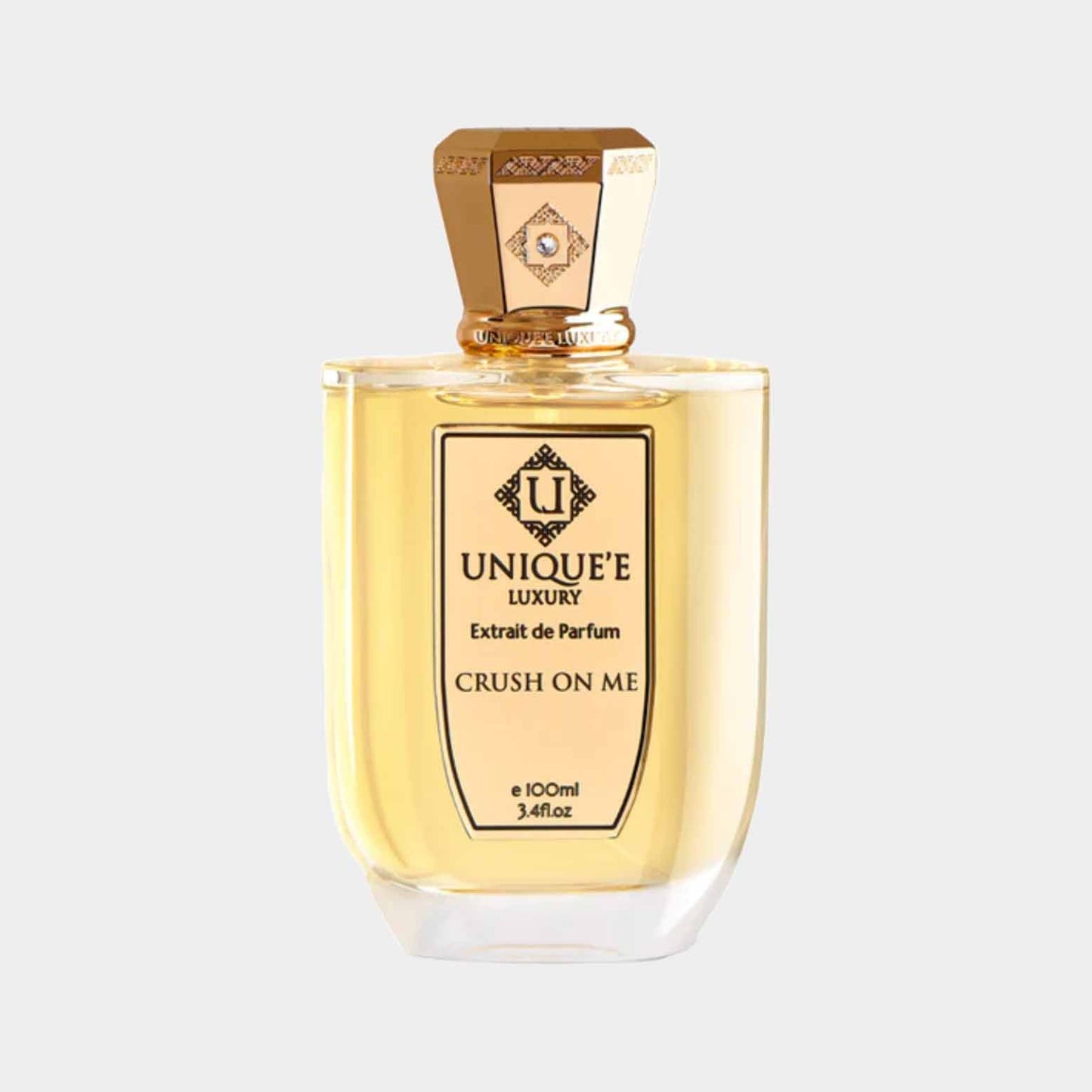 A bottle of Unique'e Luxury Crush On Me Sample, showcasing an elegant design with a gold cap and a clear liquid inside, labeled with a sophisticated logo. The bottle holds 100ml of exquisite extrait de parfum.