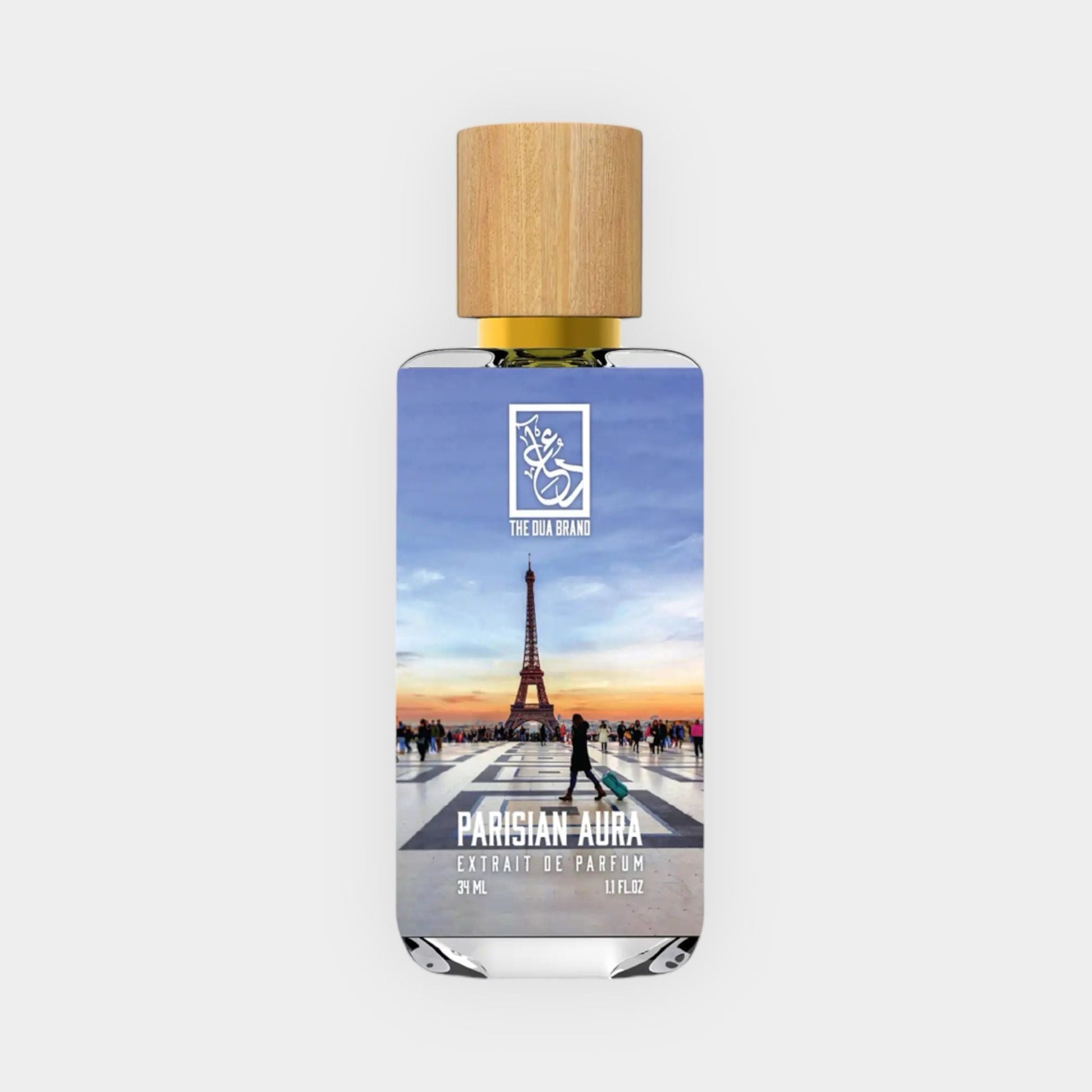 Dua Parisian Aura Sample, an elegant fragrance presented in a clear bottle featuring a wooden cap, with a picturesque image of the Eiffel Tower and a vibrant sunset backdrop.