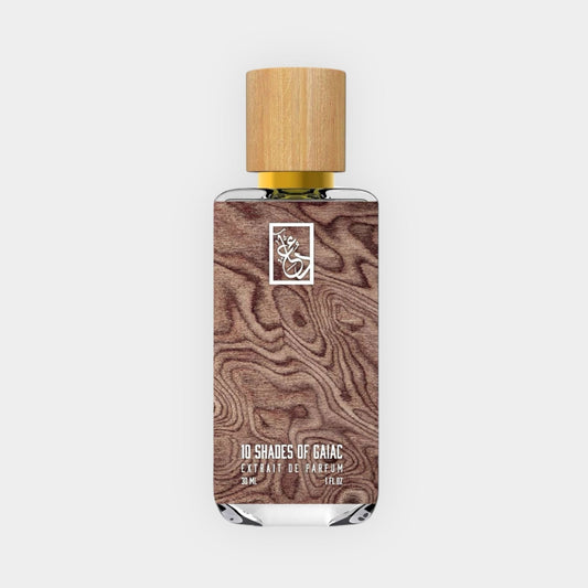 A bottle of Dua 10 Shades of Gaiac perfume, featuring a wooden cap and a sleek design with a textured wood background, contained in a 3 ml glass vial.